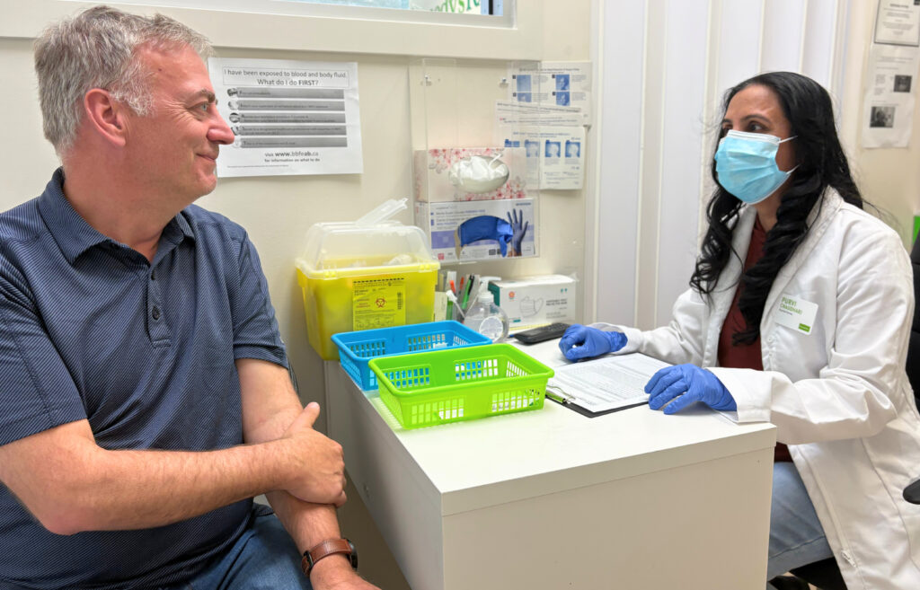 Pharmacist wearing a mask consulting with a patient during a private appointment at Royal Oak Pharmacy
